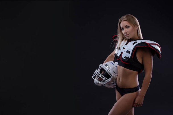 Attractive female american football player in uniform posing with helmet. girl sportswoman. Gender equality. Copy space - Foto, Imagem