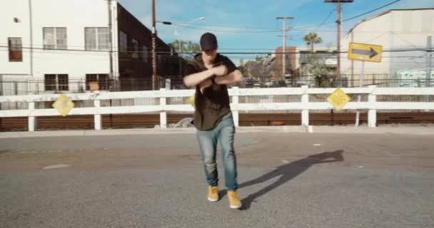 Young man dancing hip-hop on city street under blue sky - Video
