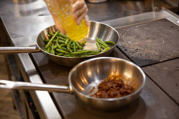 Prozess des Kochens von Fleisch und Spargel. Zutaten in Pfannen auf dem Herd Smb gießt mit Olivenöl - Foto, Bild
