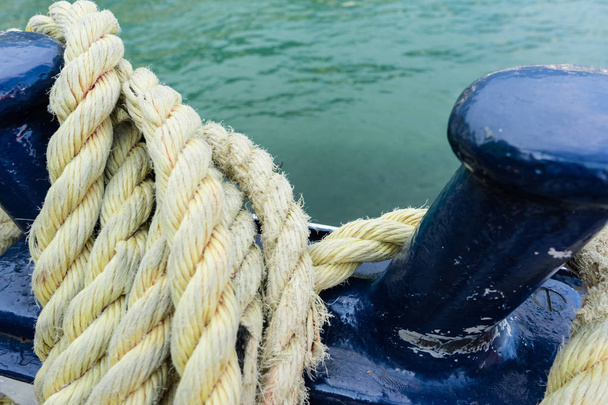 Close-up van een oude gele versleten boot touw, water achtergrond met landschap - Foto, afbeelding