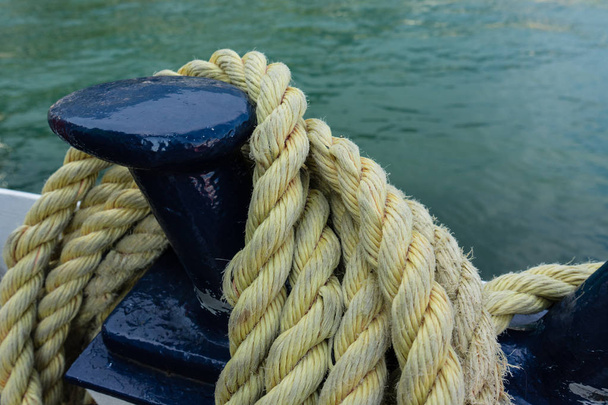 Close-up of an old yellow frayed boat rope, water background with landscape - Foto, afbeelding