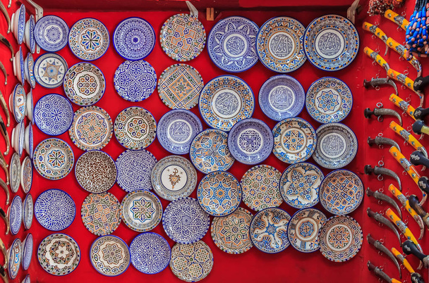 Placas decorativas y cuchillos adornados en una tienda de souvenirs oriental en el mercado o zoco en Fez, Marruecos
 - Foto, imagen