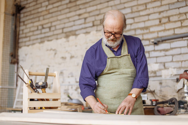 old wood worker spending time in the workshop - Foto, afbeelding