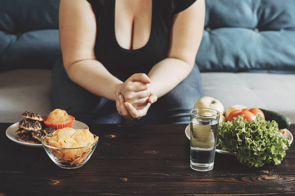 obese woman choosing between healthy and junk food - Foto, Bild