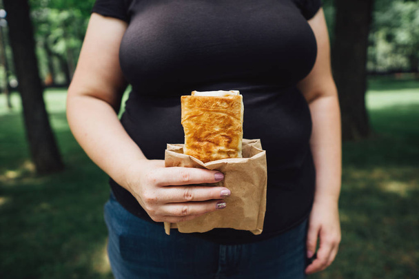 Overweight woman eats burrito walking outdoors - Photo, Image