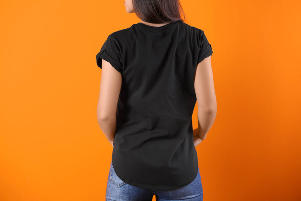 Young woman in black t-shirt on color background. Mockup for design - Foto, imagen