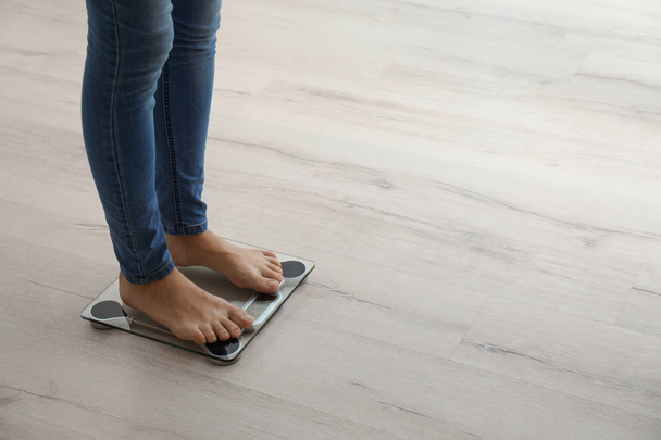 Жінка вимірює вагу, використовуючи ваги на дерев'яній підлозі. Здорова дієта
 - Фото, зображення