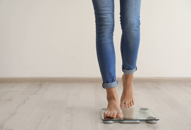 Woman measuring her weight using scales on wooden floor. Healthy diet - Фото, изображение