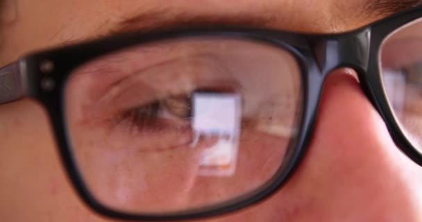 Attractive young man using smartphone while chat typing, reflection eyes in glasses close up. - Footage, Video
