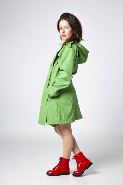 молода красива жінка в зеленій шкірі з капюшоном і червоними черевиками
  - Фото, зображення