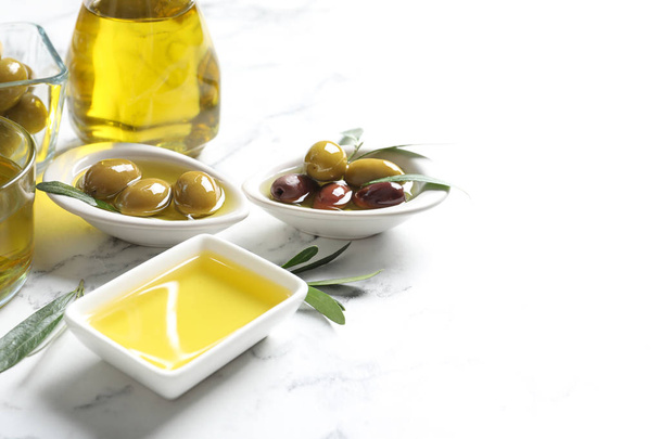 Bowls with olives and fresh oil on table - 写真・画像