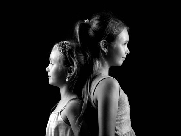 Two cute little sisters huddled together in black and white - Fotó, kép