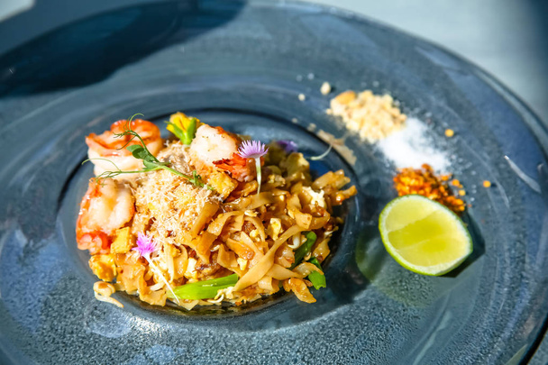 Prawn noodles lying on a plate and decorated with edible flowers, Thai cuisine - Foto, Bild