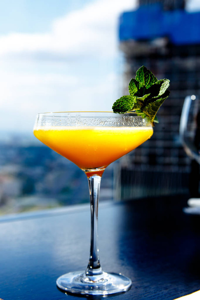 Gele mango cocktail met muntblad in een glas. - Foto, afbeelding