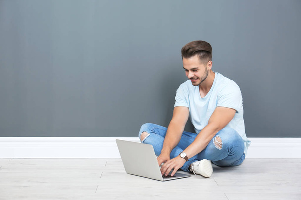 Man in casual clothes with laptop near color wall - Photo, image