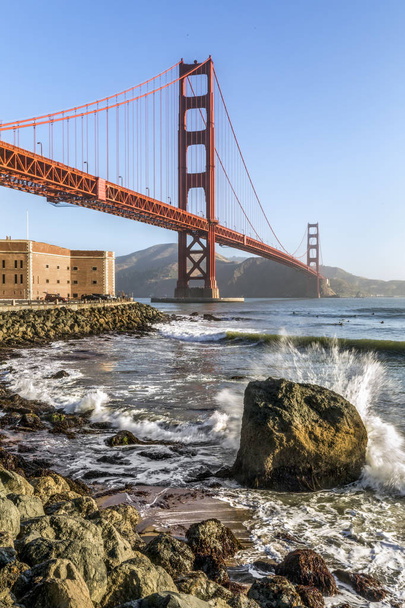 Серферы ловят ранние утренние волны под мостом Голден Гейт в районе Форт-Пойнт на открытии залива Сан-Франциско в Тихий океан
. - Фото, изображение