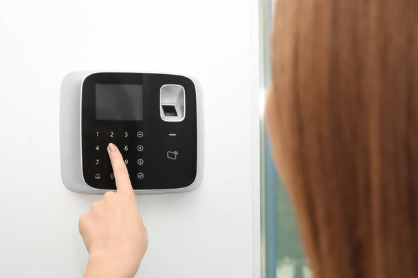 Young woman entering code on alarm system keypad indoors - Photo, Image