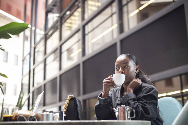 attraente giovane donna africana che beve una tazza di tè su una terrazza moderna
  - Foto, immagini