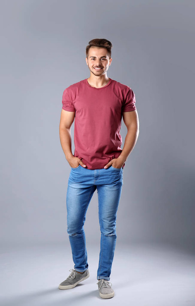 Young man in stylish jeans on grey background - Фото, зображення