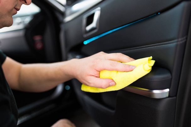 A man cleaning car with microfiber cloth, car detailing (or valeting) concept. Selective focus.  - Фото, изображение