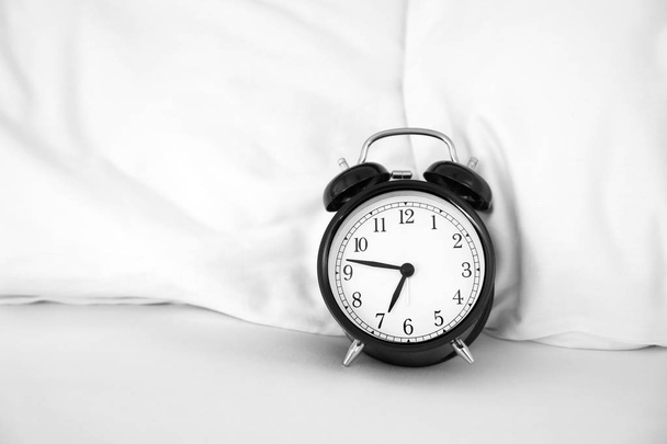 Analog alarm clock on bed. Time of day - Zdjęcie, obraz