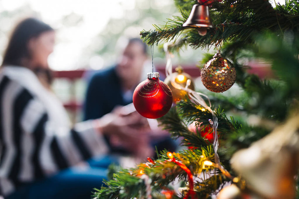 Árbol de Navidad decorado y pareja en el fondo
 - Foto, imagen