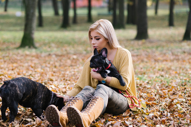 Beautiful and happy woman enjoying in park enjoying with her adorable French bulldog. Autumn time - Photo, Image