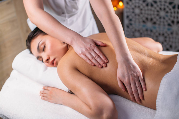 young beautiful woman with closed eyes is receiving massage for full body - Photo, Image
