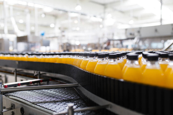 Fábrica industrial en interiores y maquinaria. Línea de fábrica robótica para el procesamiento y embotellado de botellas de refrescos y zumos de naranja
. - Foto, imagen