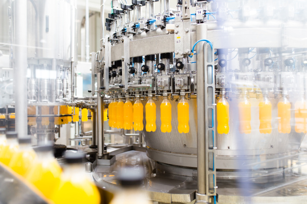 Fabryka przemysłowa wewnątrz i w maszynach. Robotyczna linia fabryczna do przetwarzania i butelkowania butelek z sodą i sokiem pomarańczowym. - Zdjęcie, obraz
