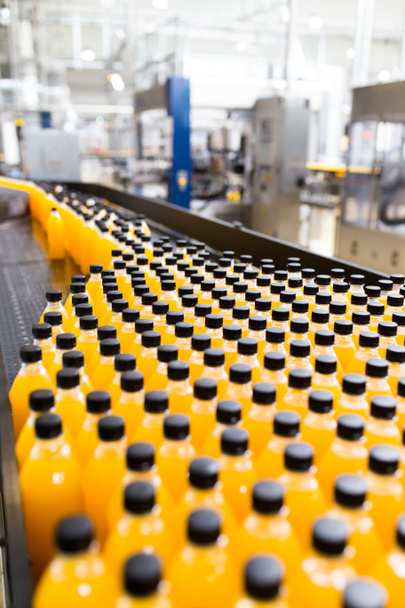 Fábrica industrial en interiores y maquinaria. Línea de fábrica robótica para el procesamiento y embotellado de botellas de refrescos y zumos de naranja
. - Foto, Imagen