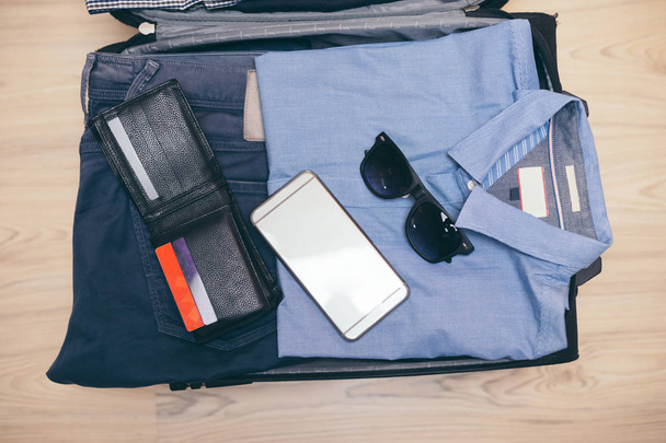 Bolsa de viaje abierta con ropa de hombre, accesorios
 - Foto, Imagen
