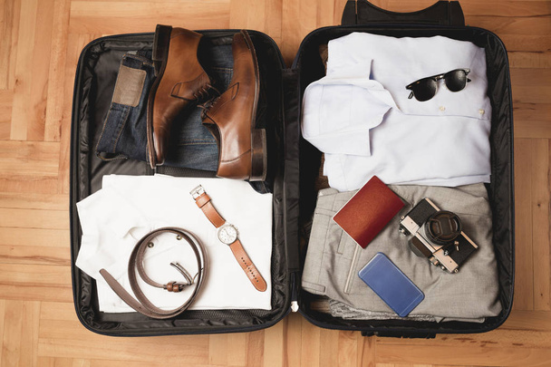 Відкрита сумка мандрівника з чоловічим одягом, аксесуарами
 - Фото, зображення