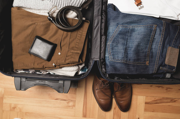 Bolsa de viaje abierta con ropa de hombre, accesorios
 - Foto, imagen