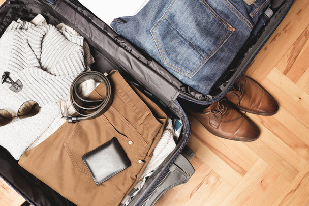 Відкрита сумка мандрівника з чоловічим одягом, аксесуарами
 - Фото, зображення