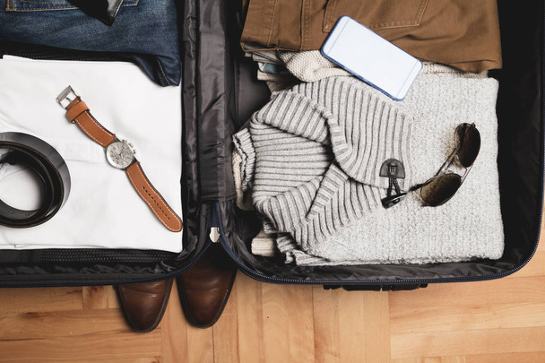 Open traveler's zak met mannen kleding, accessoires - Foto, afbeelding