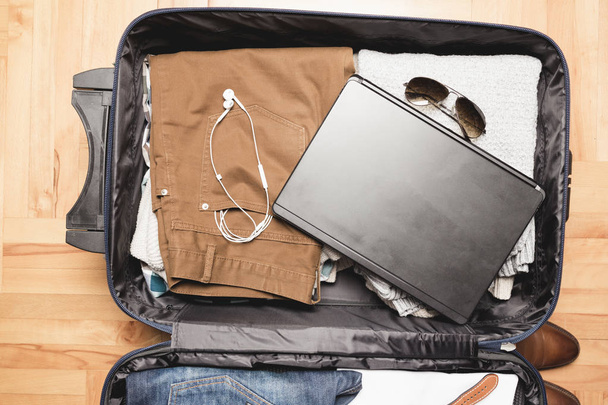 Open traveler's bag with men clothing, accessories - Foto, imagen