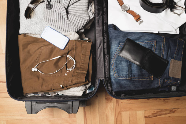 Open traveler's bag with men clothing, accessories - Фото, изображение