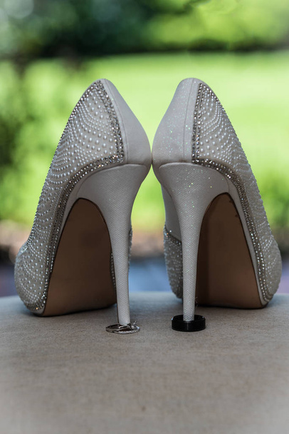 Στιλέτο ψηλοτάκουνα παπούτσια της νύφης κρατάει η σύζυγος και η σύζυγος Βέρες στη θέση. - Φωτογραφία, εικόνα