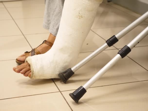 Ασθενής περιμένει με σπασμένο πόδι και δεκανίκια στο δωμάτιο του νοσοκομείου  - Πλάνα, βίντεο