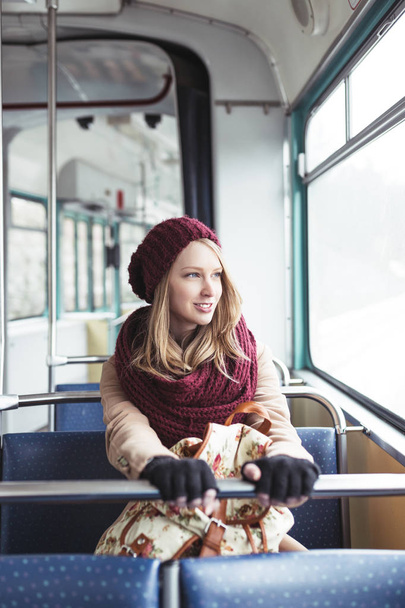 Beautiful young woman sitting in tram and looking through window.  - Photo, Image