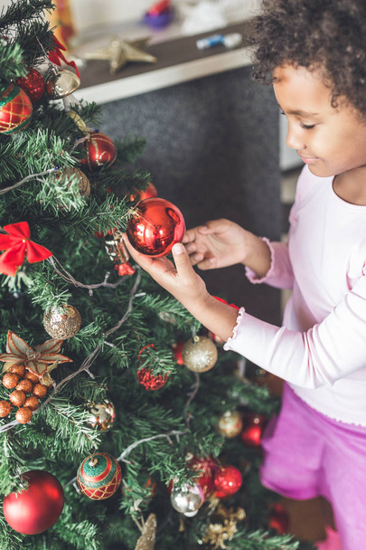 little girl decorating the Christmas tree. Natural light - Photo, Image