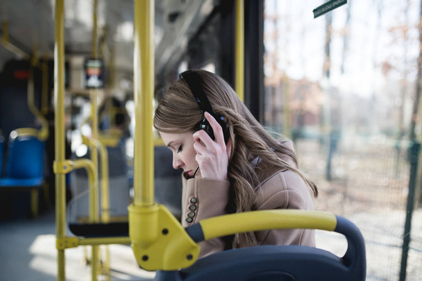 美しい幸せな若い女バスに座っていると、音楽を聴く.  - 写真・画像