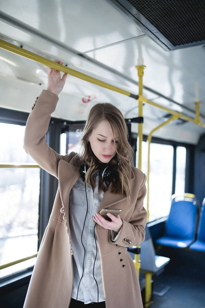 Kaunis onnellinen nuori nainen kaupungin bussissa matkapuhelimella
 - Valokuva, kuva