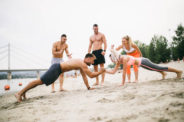 Groupe de jeunes gens attrayants qui s'amusent à la plage et font un peu de fitness
. - Photo, image