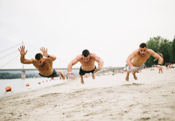 Skupina mladých atraktivních lidí, kteří se baví na pláži a dělají fitness cvičení. - Fotografie, Obrázek