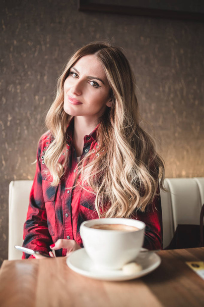 美しい若い女性カフェ レストランに座って、リラックスしてコーヒーを飲む.  - 写真・画像