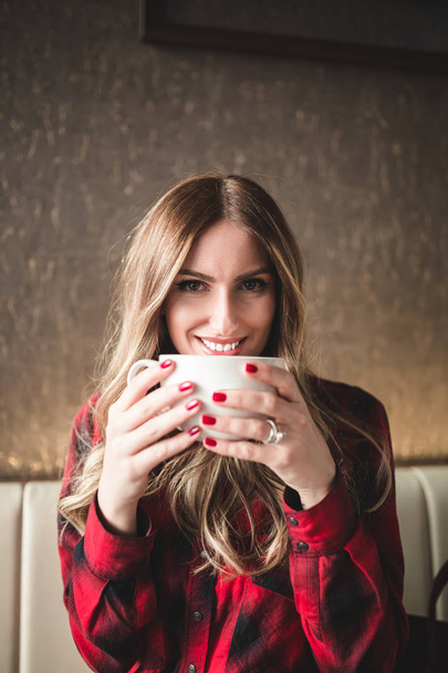 Piękna młoda kobieta siedzi w restauracji café, relaksujące i picia kawy.  - Zdjęcie, obraz