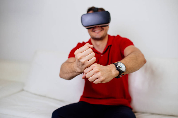 Nuori mies yllään virtuaalitodellisuus suojalasit ja pelaa videopeliä
 - Valokuva, kuva