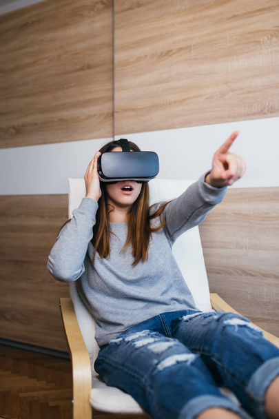 Beautiful teenage girl wearing virtual reality goggles and playing video game - Photo, image